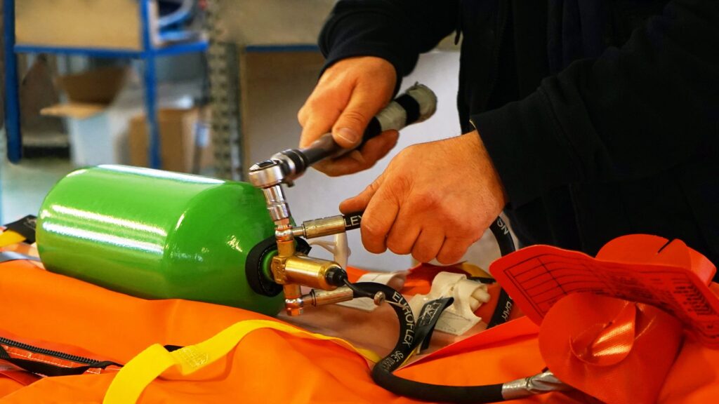 Tecnico che collega bombola di ossigeno durante la manutenzione di attrezzature di sicurezza in ambiente industriale.