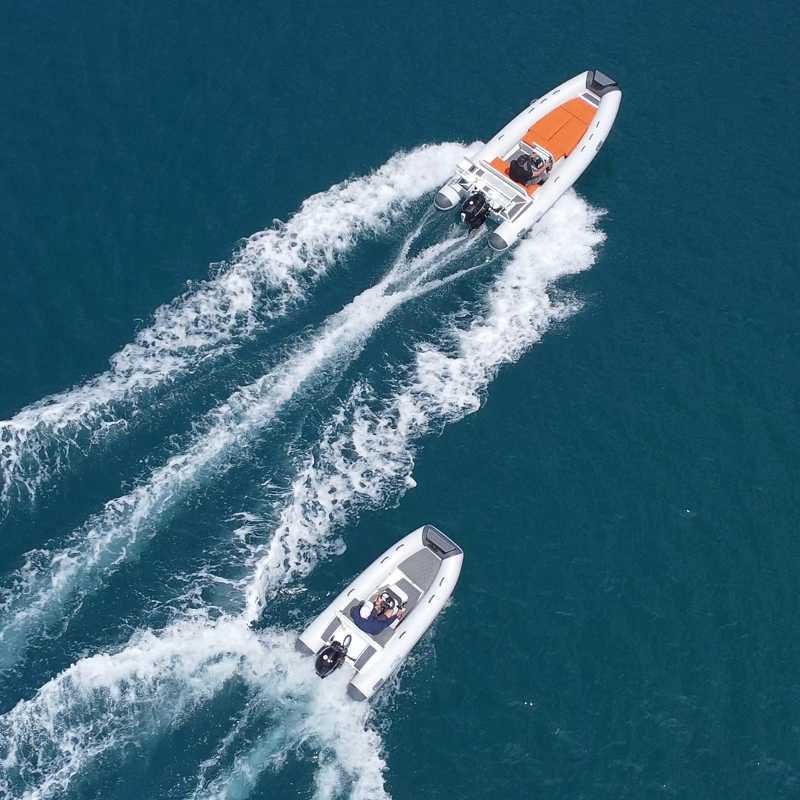 Due gommoni navigano a velocità su acqua blu vista dall'alto.