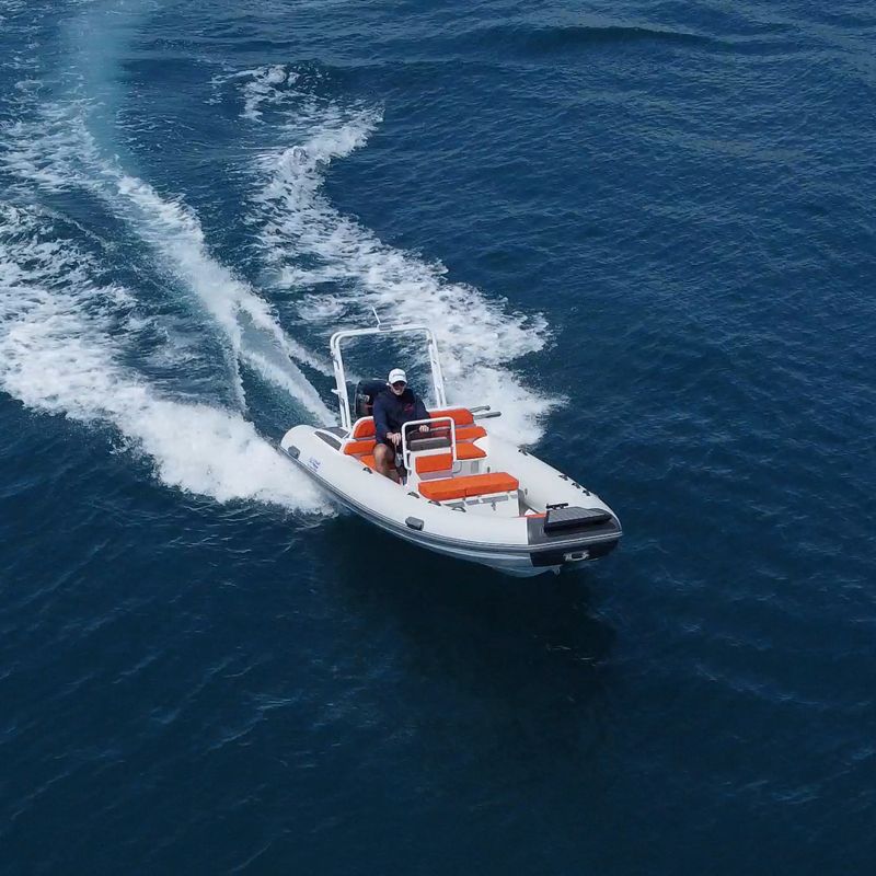 Gommone veloce in mare aperto con pilota, sedili arancioni e scia d'acqua, navigazione estiva divertente.